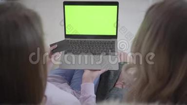 两个女孩正在笔记本电脑上通过<strong>绿色</strong>屏幕<strong>上网</strong>寻找优惠折扣